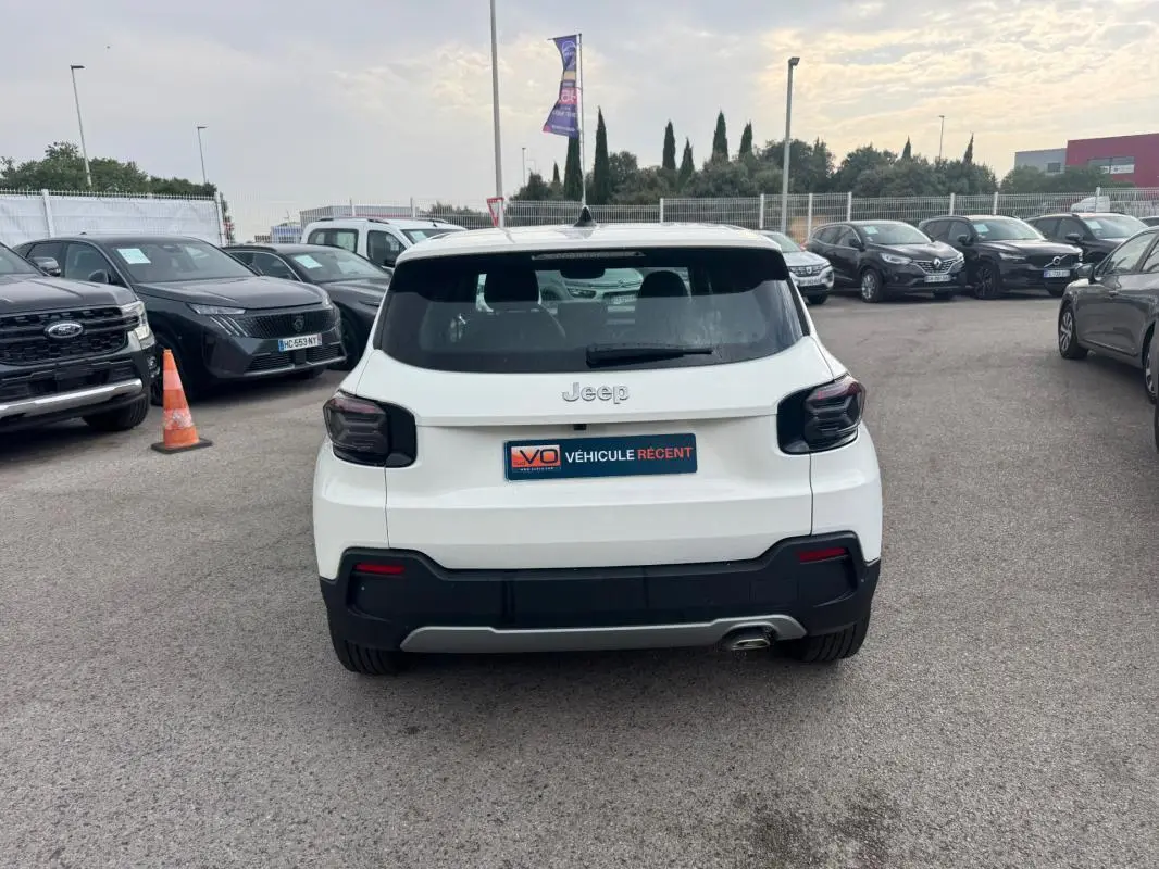 Vue arrière d'un Jeep Avenger blanc 2025 avec feux arrière fumés et plaque V.O. Véhicule Récent visible.