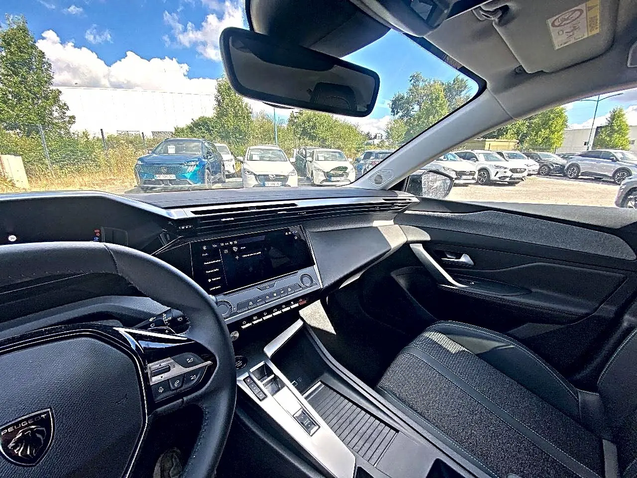Vue intérieure côté conducteur de la Peugeot 308 gris 2025, avec tableau de bord moderne et écran tactile central.