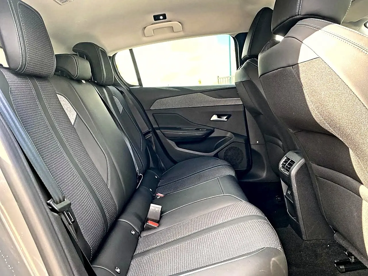 Vue intérieure côté droit sur la banquette arrière noire et grise de la Peugeot 308 2025, avec appuie-têtes et ceintures visibles.