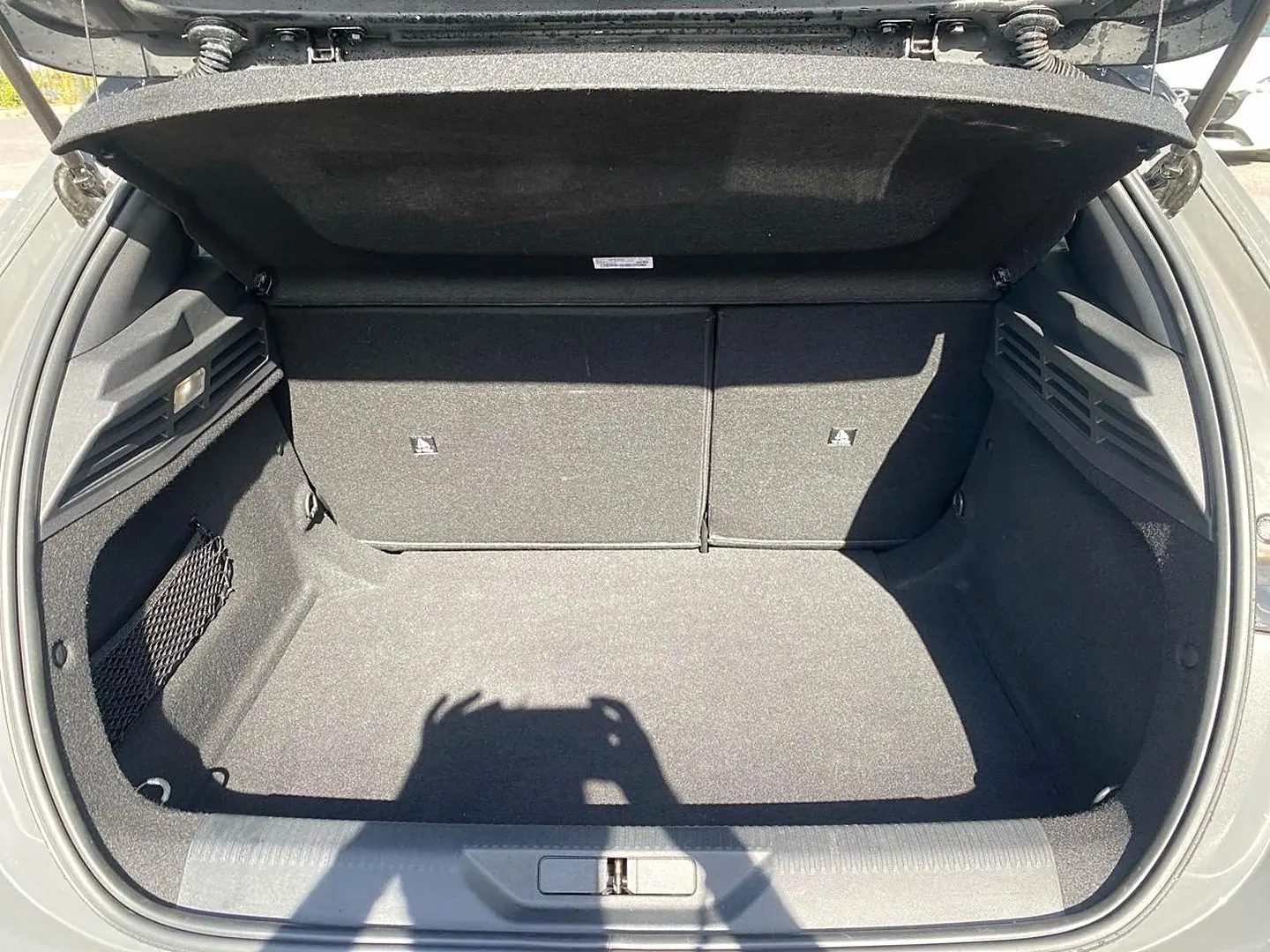 Coffre ouvert vu de l'arrière d'une Peugeot 308 gris, montrant un espace de chargement propre et bien fini.
