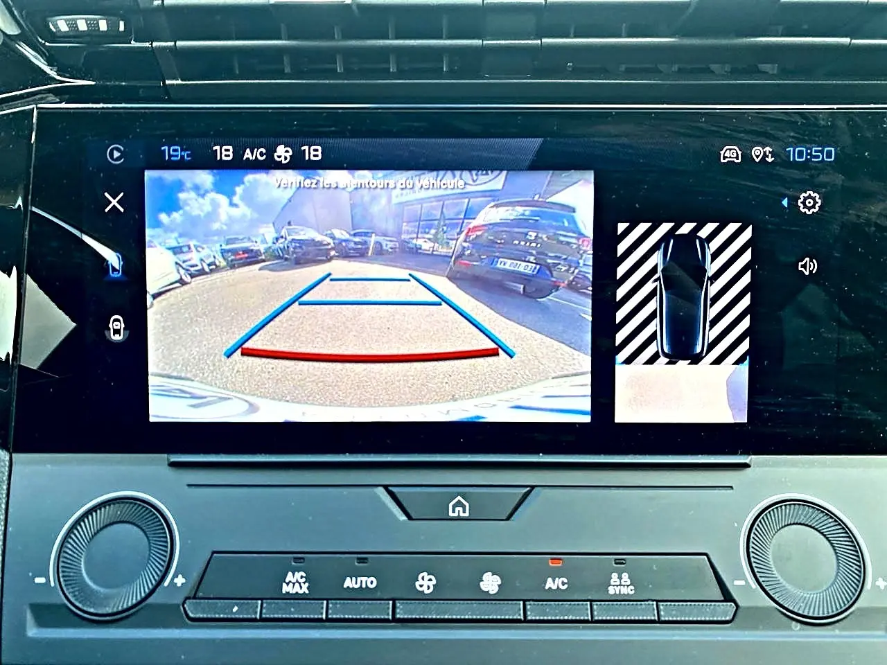 Écran tactile intérieur montrant la caméra de recul active d'une Peugeot 308 gris, avec affichage des aides au stationnement.