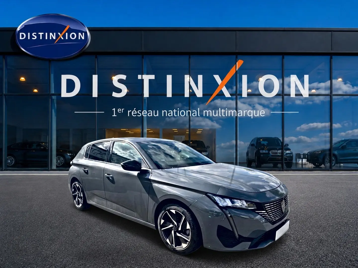 Peugeot 308 gris vue 3/4 avant droit, avec jantes alliage et calandre distinctive, devant showroom Distinxion.