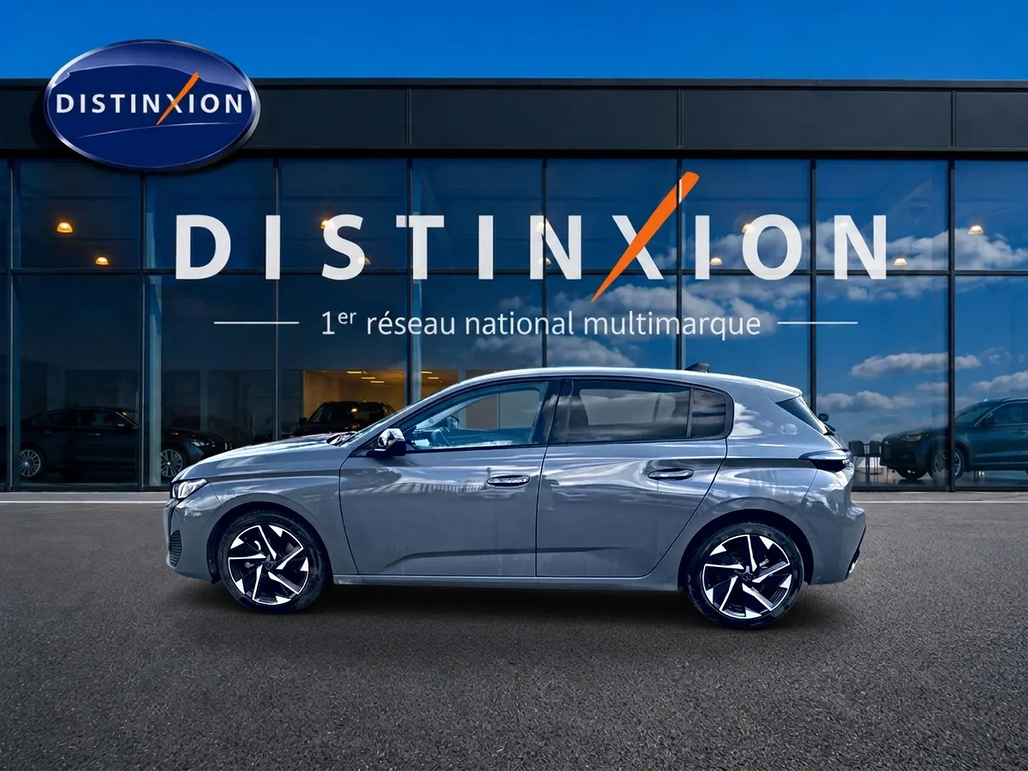 Peugeot 308 gris vue de profil côté gauche, avec jantes alliage et vitres arrière surteintées devant un showroom Distinxion.
