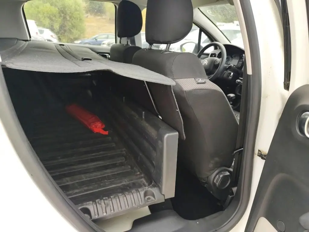 Vue intérieure côté droit du coffre utilitaire d'une Citroën C3 Société blanche, montrant l'espace de chargement et les sièges avant noirs.