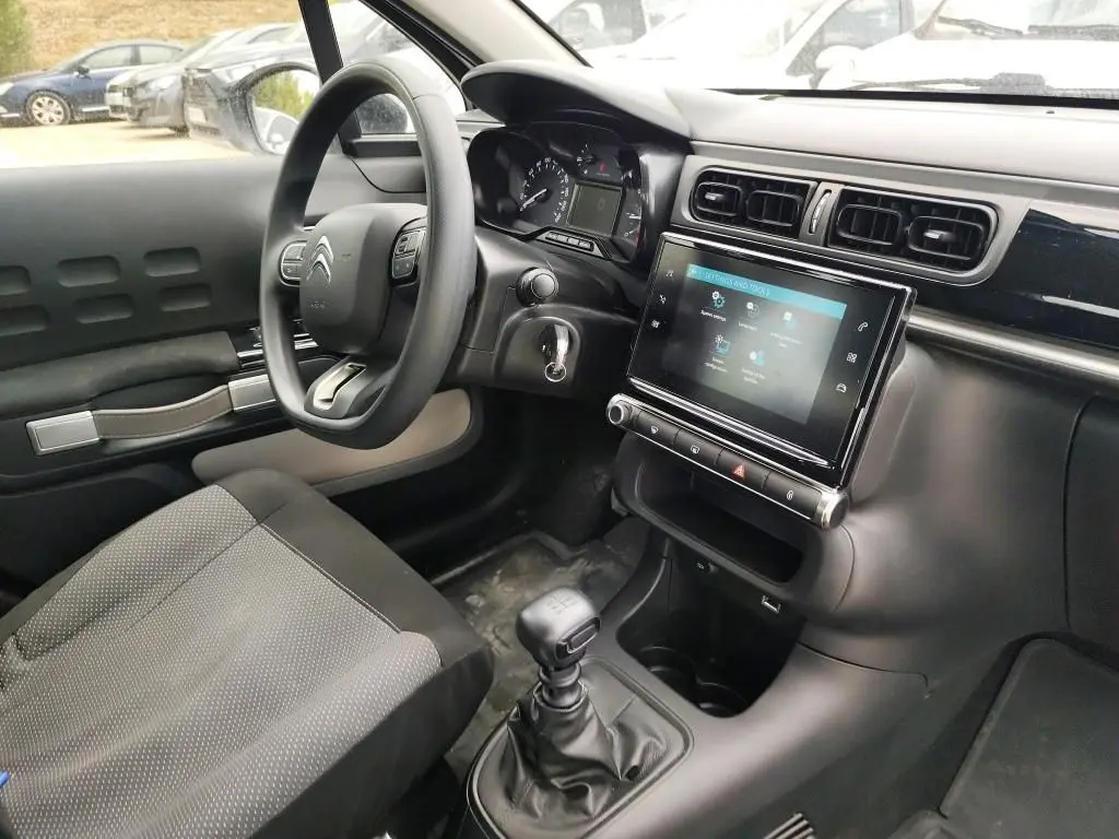 Vue intérieure côté conducteur de la Citroën C3 Société blanche, montrant le volant, la console tactile et la boîte manuelle.
