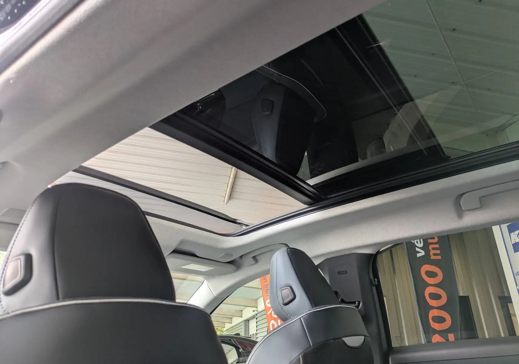 Vue intérieure du toit panoramique ouvert et des appuie-têtes en cuir noir du Citroën C5 Aircross hybride 2026.
