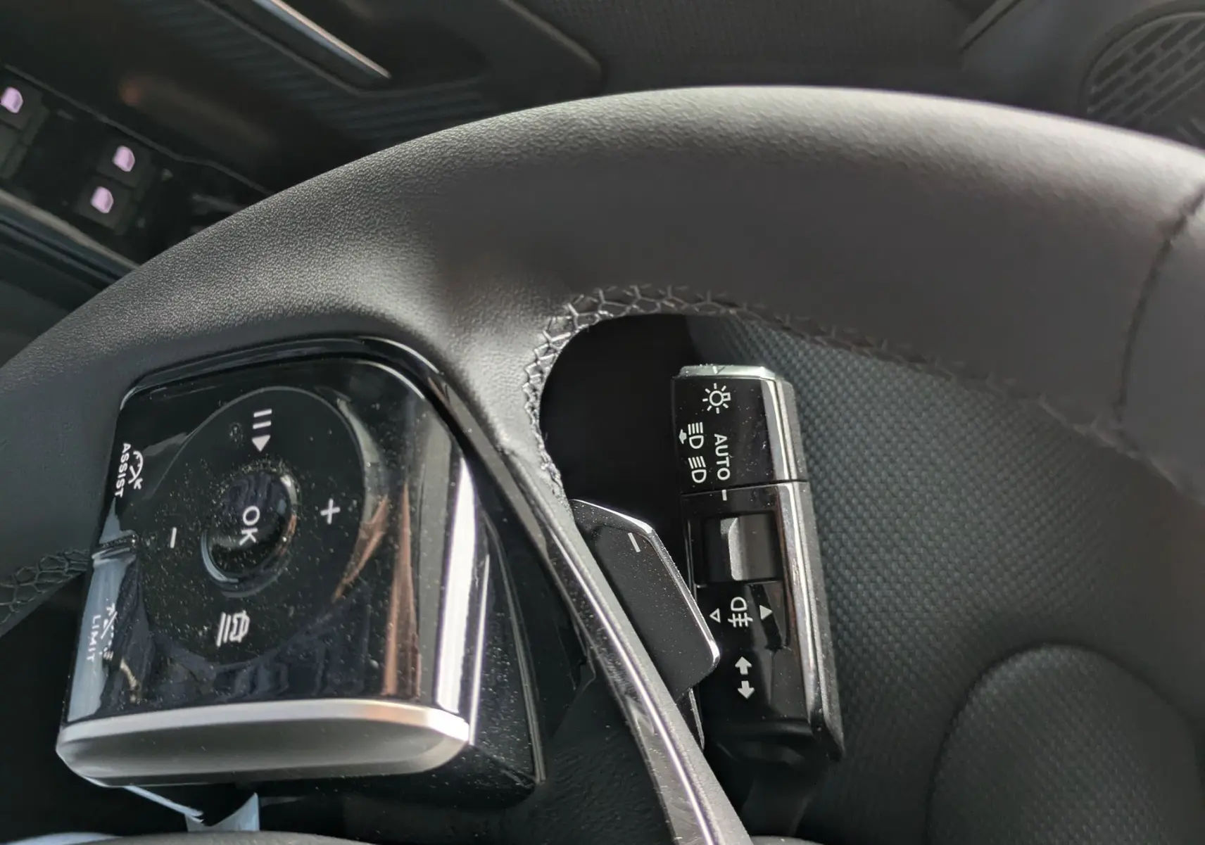 Gros plan sur le volant et la commande d’éclairage du Citroën C5 Aircross hybride, intérieur noir texturé.