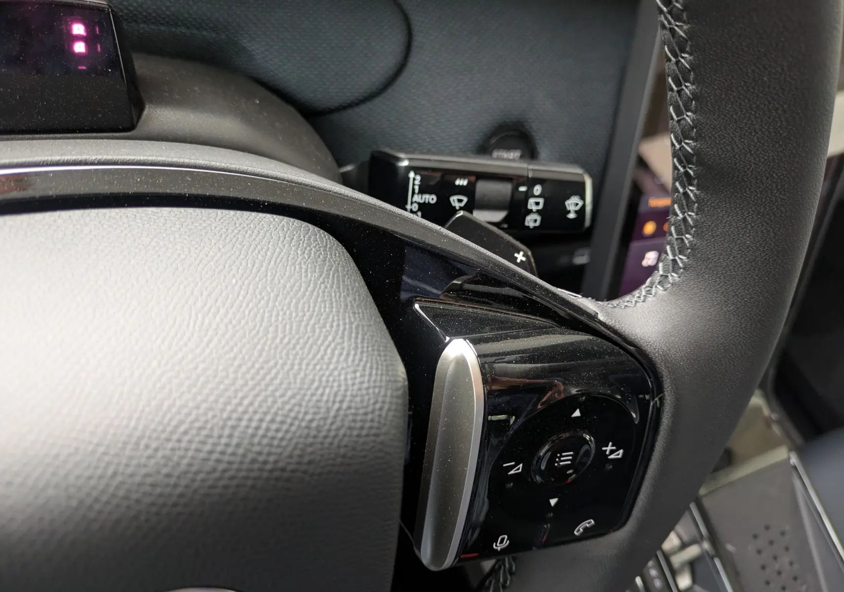 Gros plan sur la commande multifonction droite du volant en cuir noir du Citroën C5 Aircross hybride 2026.