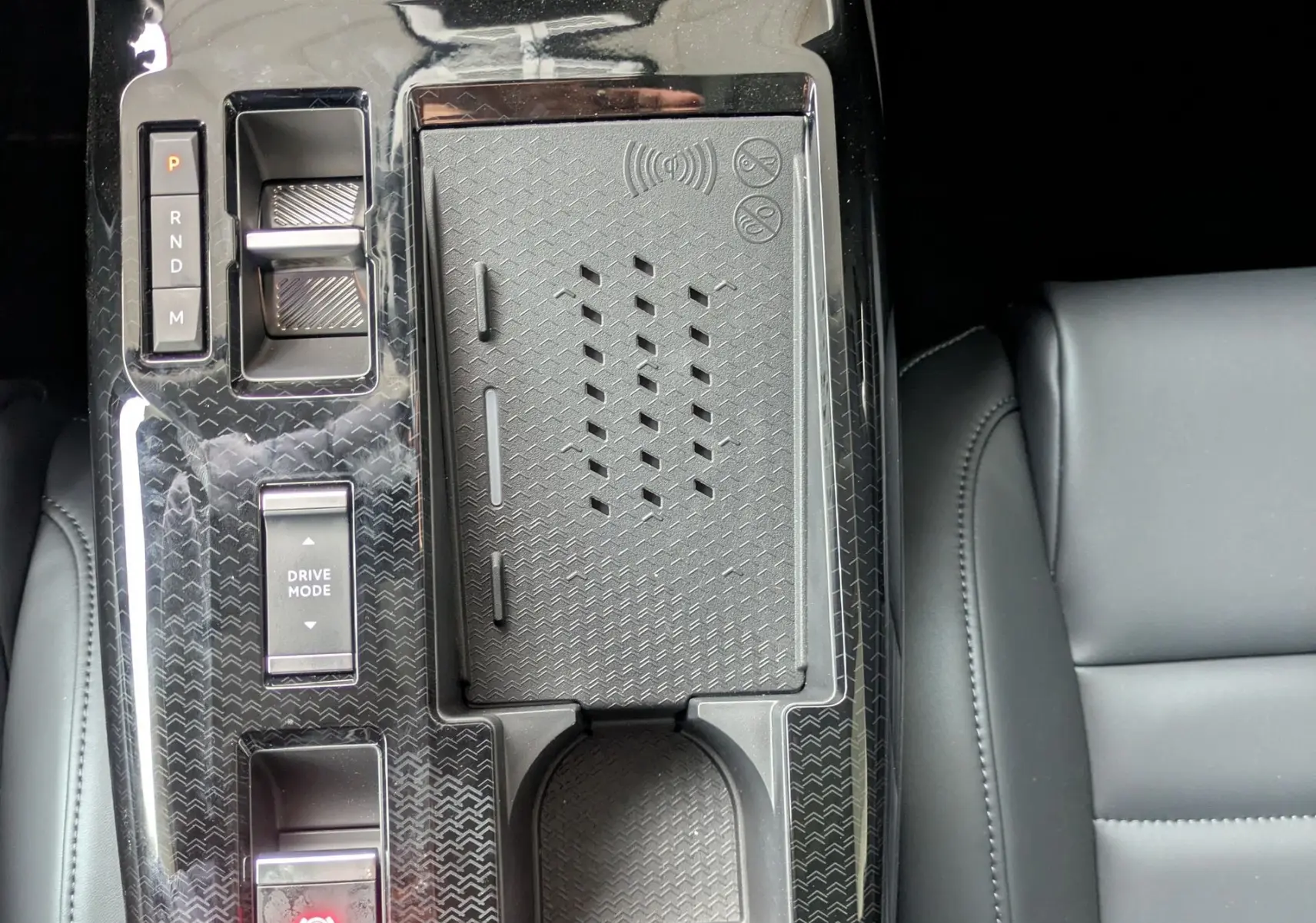Vue plongeante sur la console centrale noire brillante du Citroën C5 Aircross hybride 2026 avec commandes et porte-gobelet.