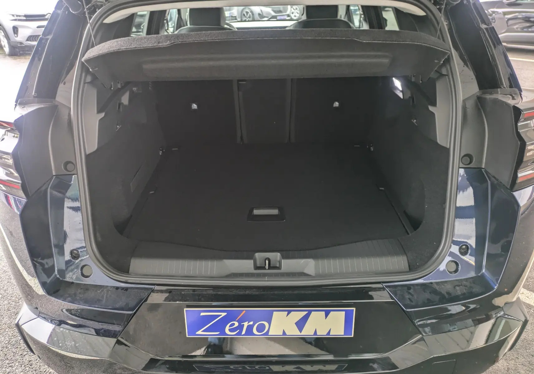Coffre ouvert vu de l'arrière d'un Citroën C5 Aircross hybride bleu eclipse avec toit noir et hayon ouvert.