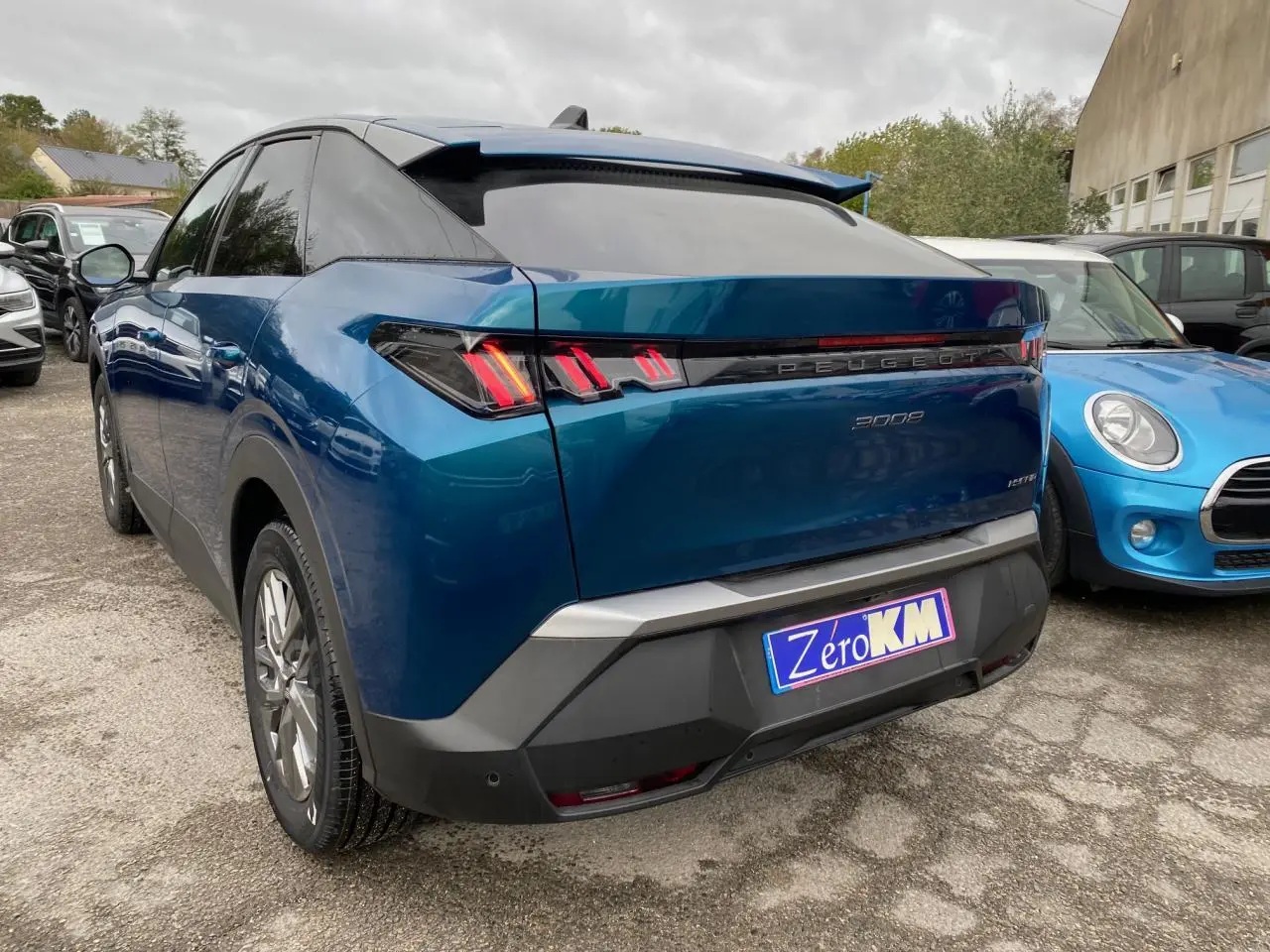 Vue 3/4 arrière droite d'un Peugeot 3008 hybride bleu Obsession avec feux arrière à LED et logo Peugeot lumineux.
