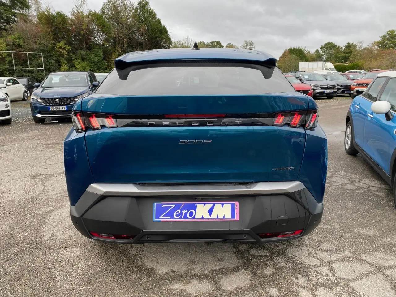 Vue arrière d’un Peugeot 3008 hybride bleu Obsession avec feux arrière à trois griffes et logo central lumineux.