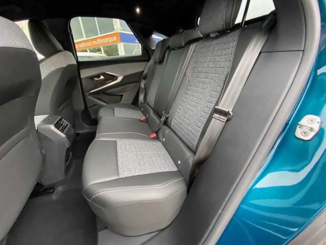 Vue intérieure côté droit des sièges arrière gris et noir du Peugeot 3008 Bleu Obsession avec ceinture de sécurité attachée.