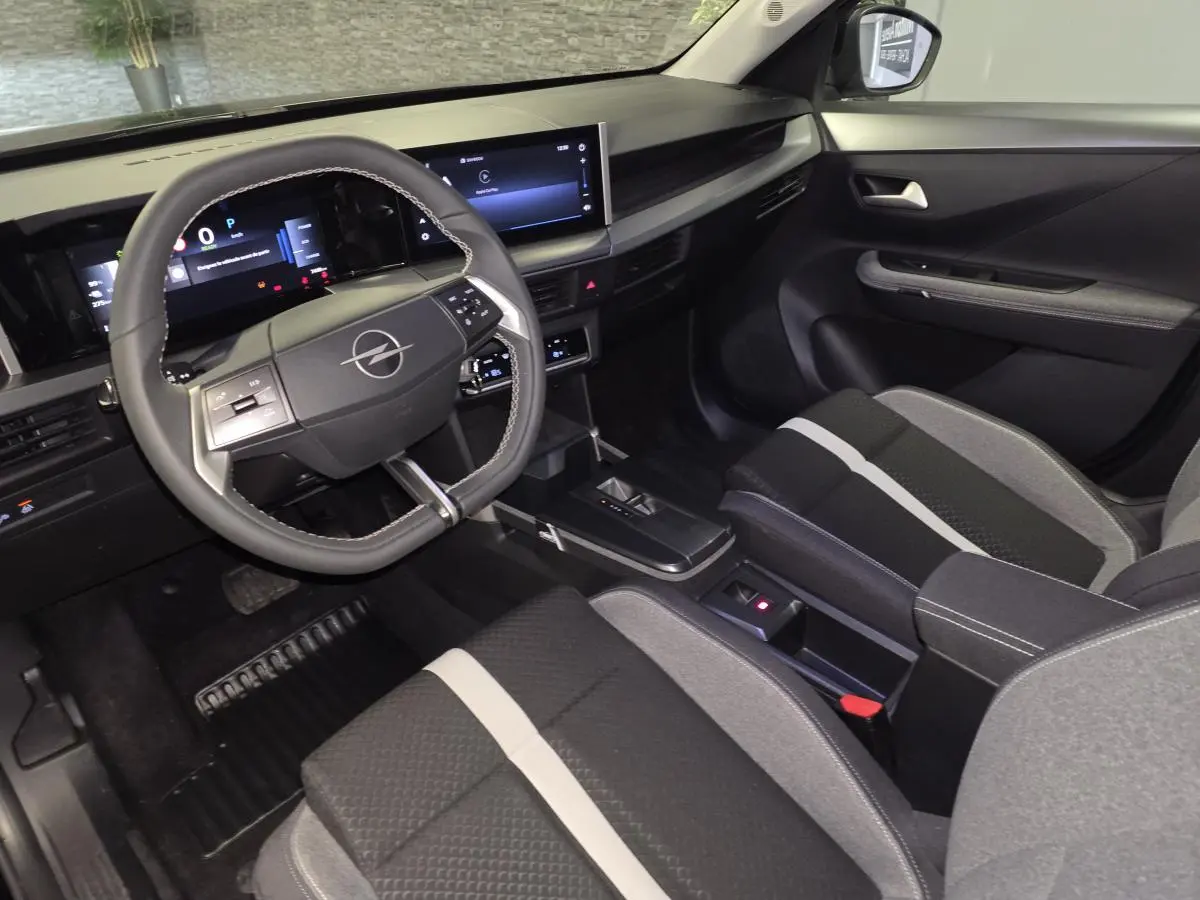 Vue intérieure côté conducteur de l'Opel Frontera-e 2025, avec tableau de bord numérique et sellerie tissu gris et noir.