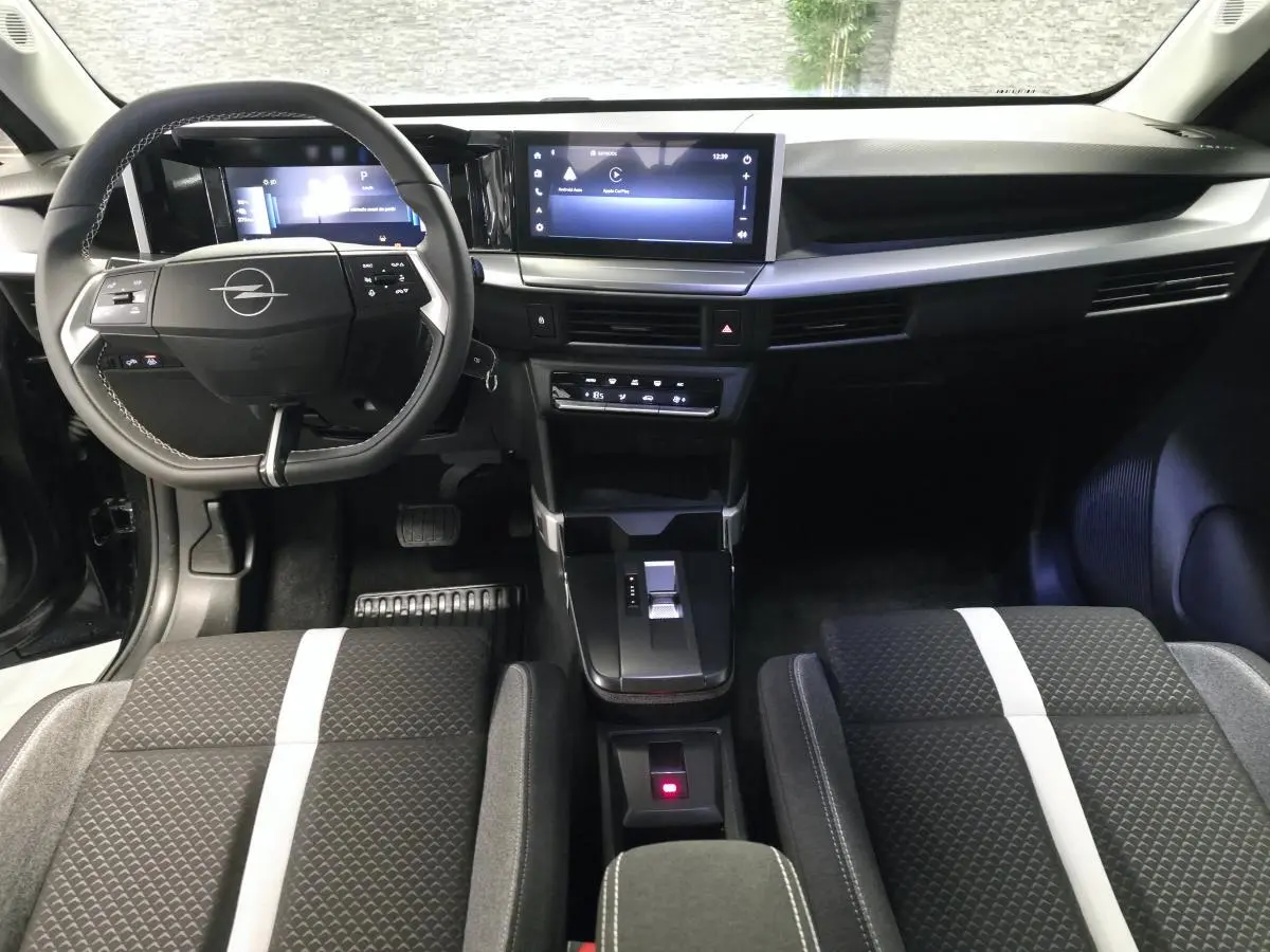 Vue intérieure avant de l’Opel Frontera-e 2025, tableau de bord noir avec écran tactile 10'' et sièges tissu à bande blanche centrale.