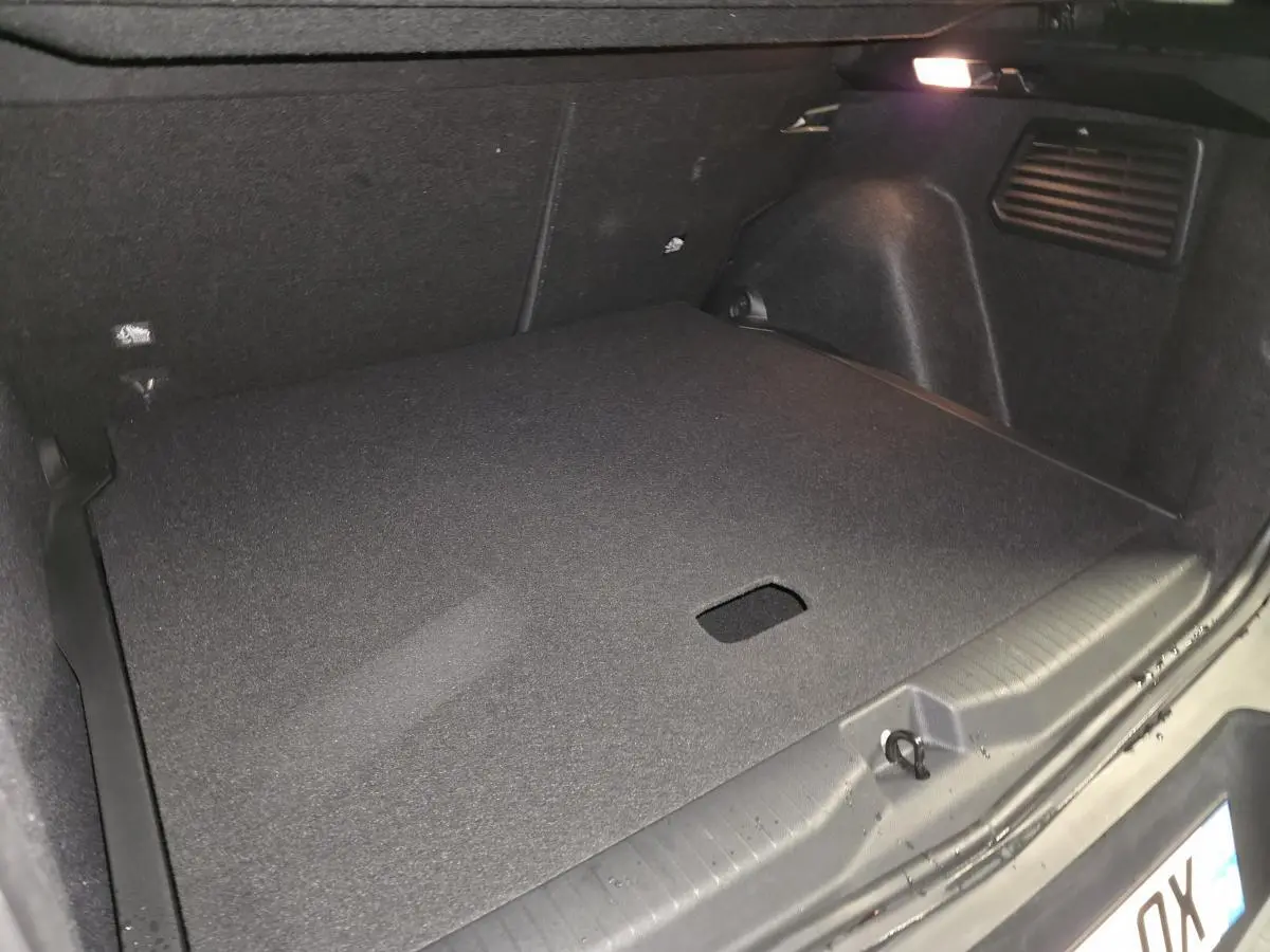 Coffre spacieux de l’Opel Frontera-e 2025 noir, vue intérieure arrière avec plancher modulable et éclairage intégré.