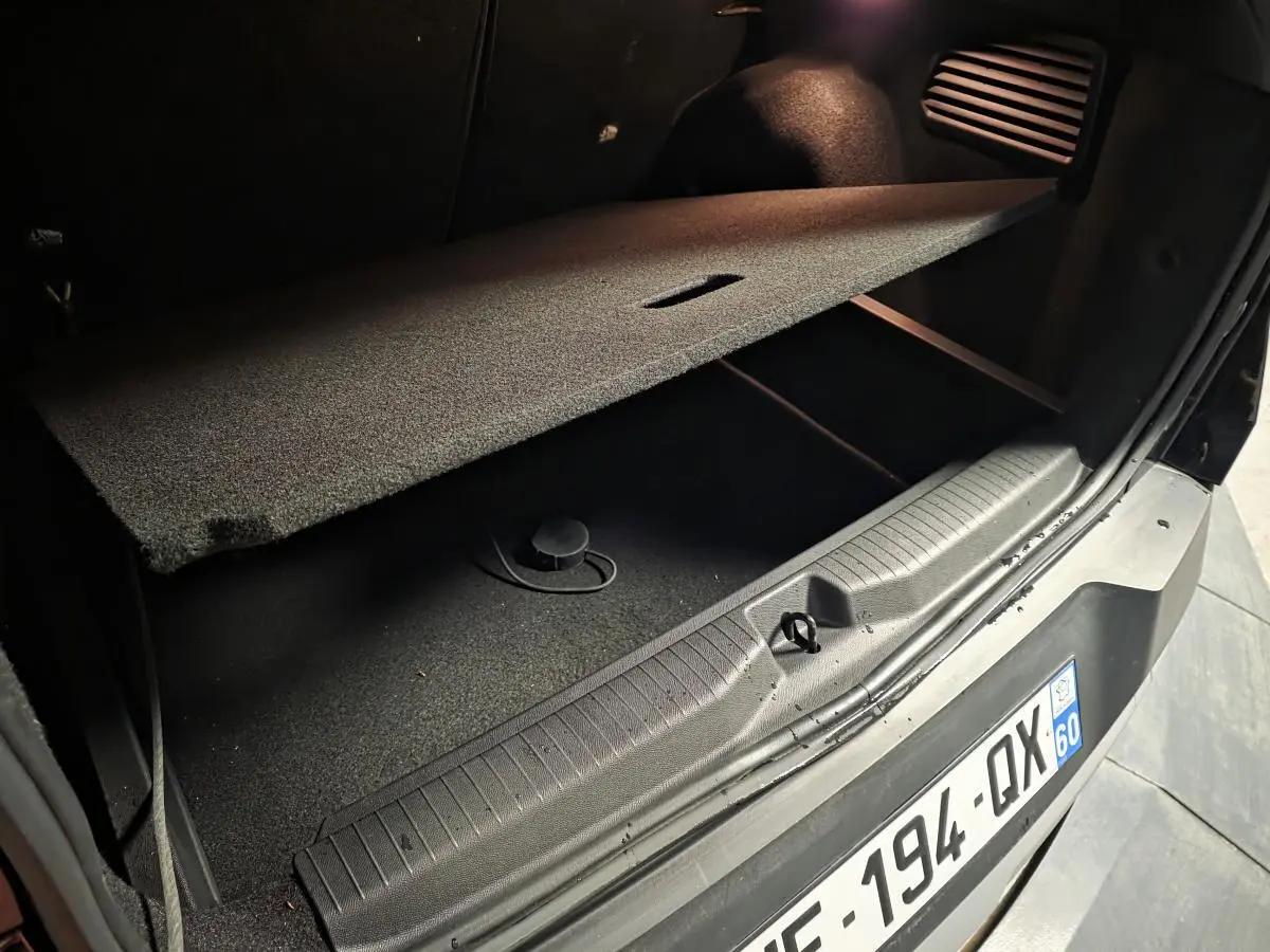 Coffre ouvert en vue rapprochée d’un Opel Frontera-e noir, montrant le plancher modulable et la plaque d’immatriculation arrière.