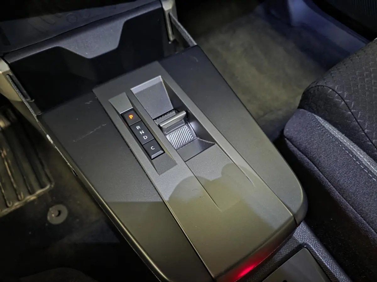 Gros plan sur la console centrale noire de l'Opel Frontera-e 2025 avec levier de boîte automatique et sièges tissu noirs.