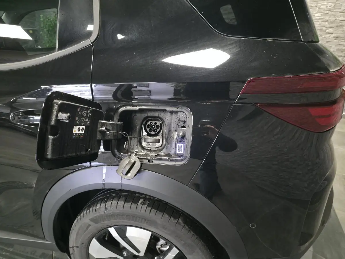 Vue arrière côté gauche d'une Opel Frontera-e noire avec trappe de recharge électrique ouverte et jante alliage 17 pouces.