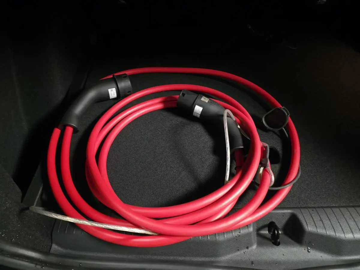 Câble de recharge électrique rouge enroulé dans le coffre d’un Opel Frontera-e noir, vue intérieure arrière.