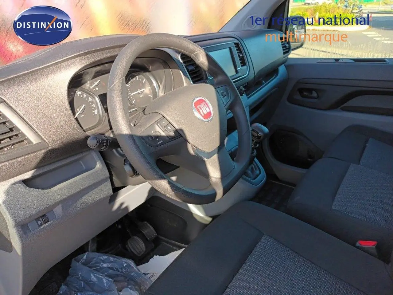 Intérieur du Fiat Scudo Fourgon 2022 montrant le tableau de bord et volant côté conducteur avec sièges tissu gris noir.
