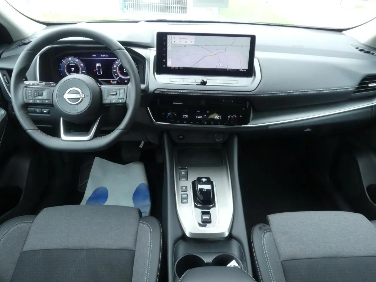 Vue intérieure avant du Nissan Qashqai 1.5 e-Power 2025, tableau de bord moderne avec écran tactile et volant cuir noir.