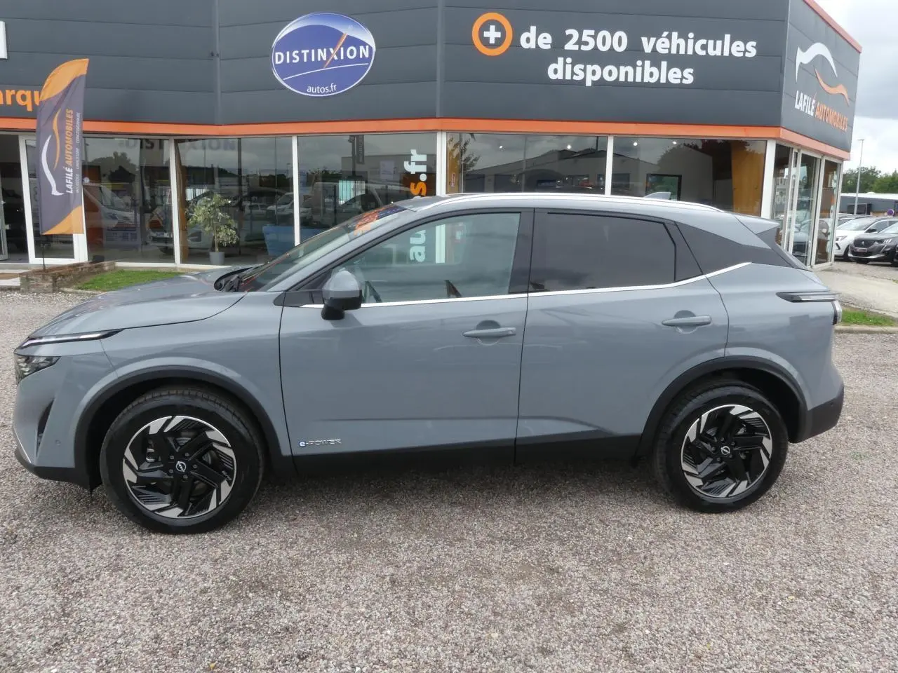 Vue latérale gauche du Nissan Qashqai 1.5 e-Power gris métallisé avec jantes alliage et vitres teintées.
