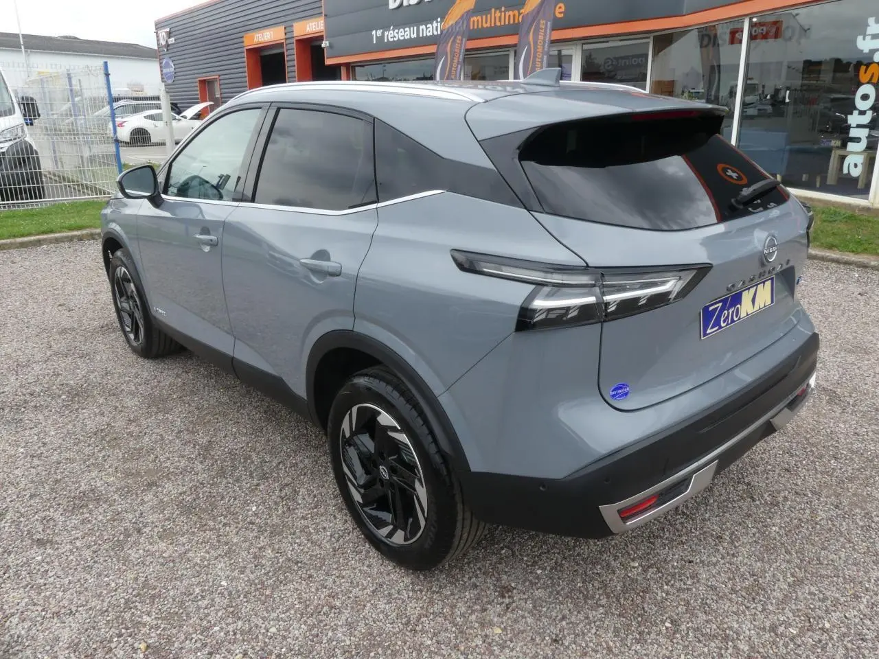 Vue 3/4 arrière droite du Nissan Qashqai 1.5 e-Power gris métallisé avec vitres teintées et jantes alliage noires.