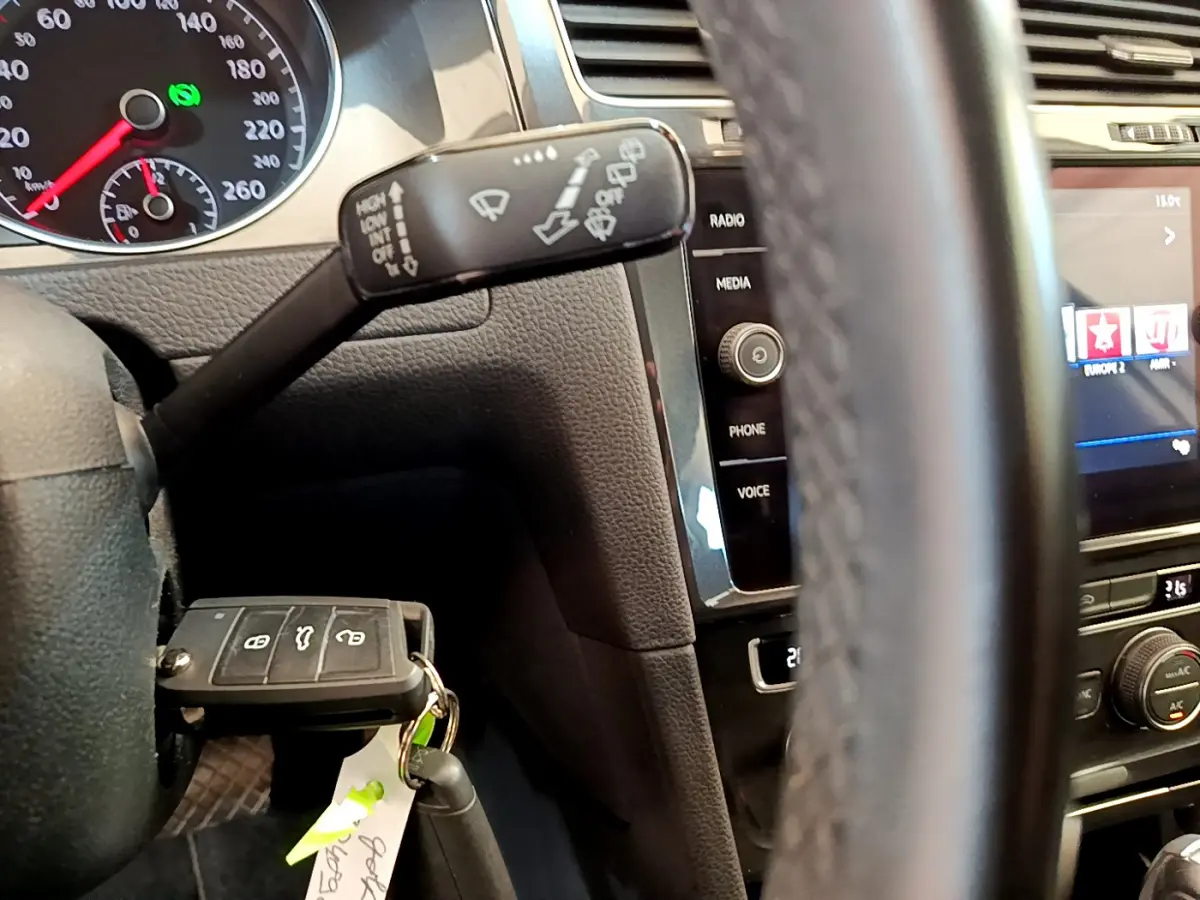 Gros plan sur le volant et tableau de bord noir d'une Volkswagen Golf 2019, avec clé insérée et commandes multimédia visibles.