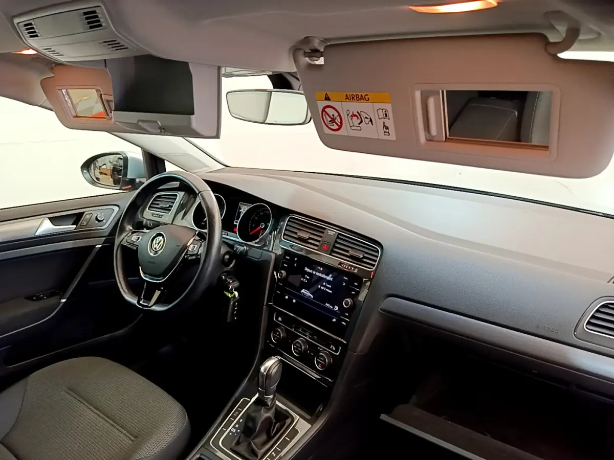Intérieur avant droit de la Volkswagen Golf gris clair 2019, volant cuir, écran tactile et tableau de bord visible.