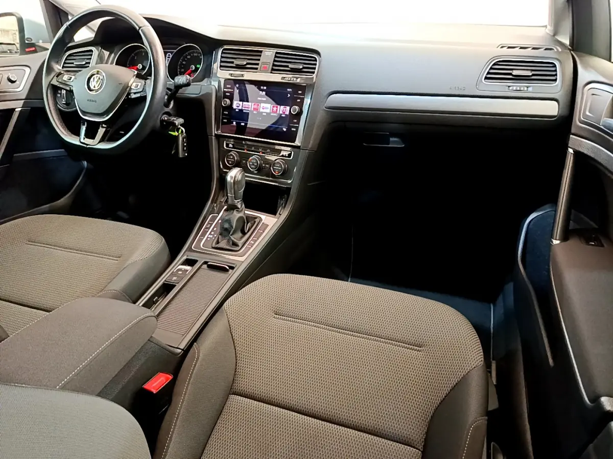 Vue intérieure avant droite de la Volkswagen Golf 1.6 TDI 2019 avec sièges gris et écran tactile central lumineux.