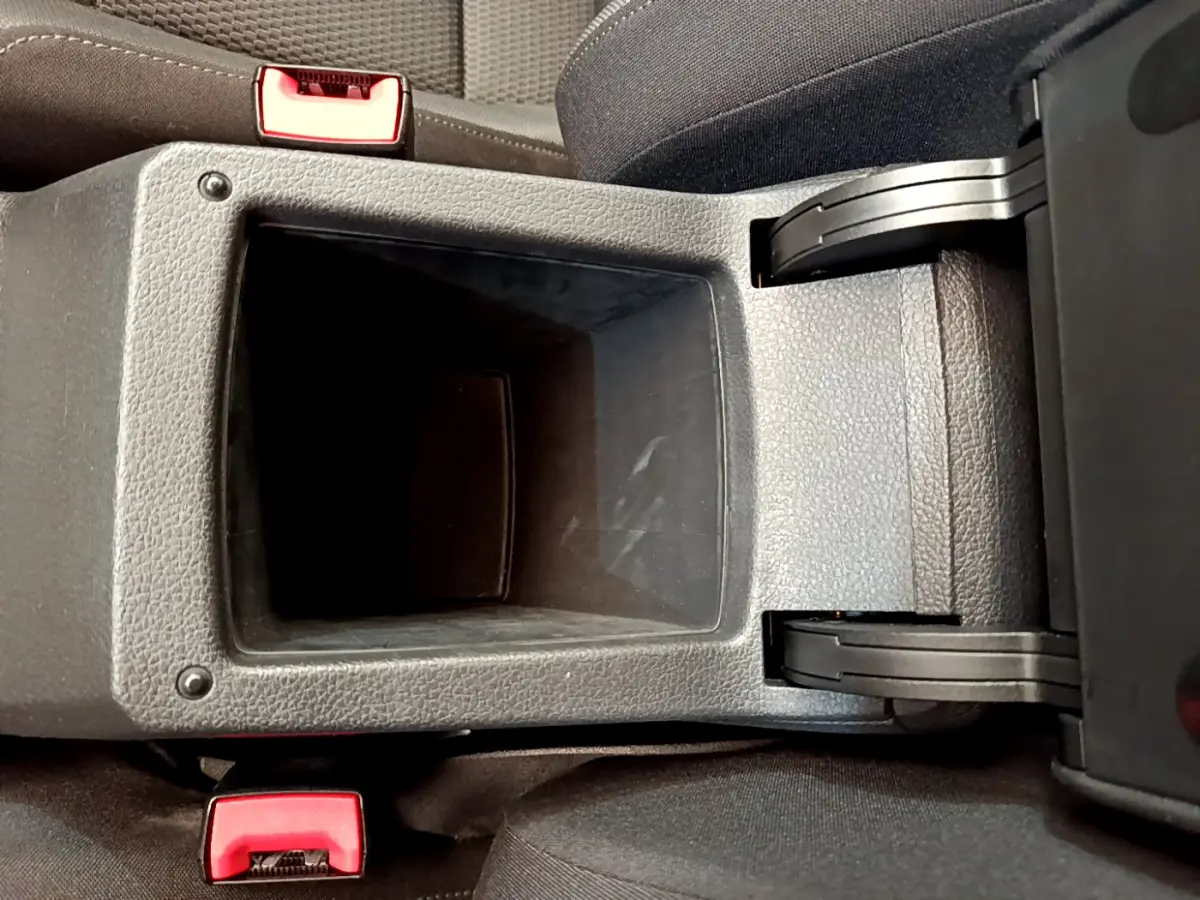 Vue plongeante sur le rangement central ouvert entre les sièges avant d'une Volkswagen Golf gris clair de 2019.