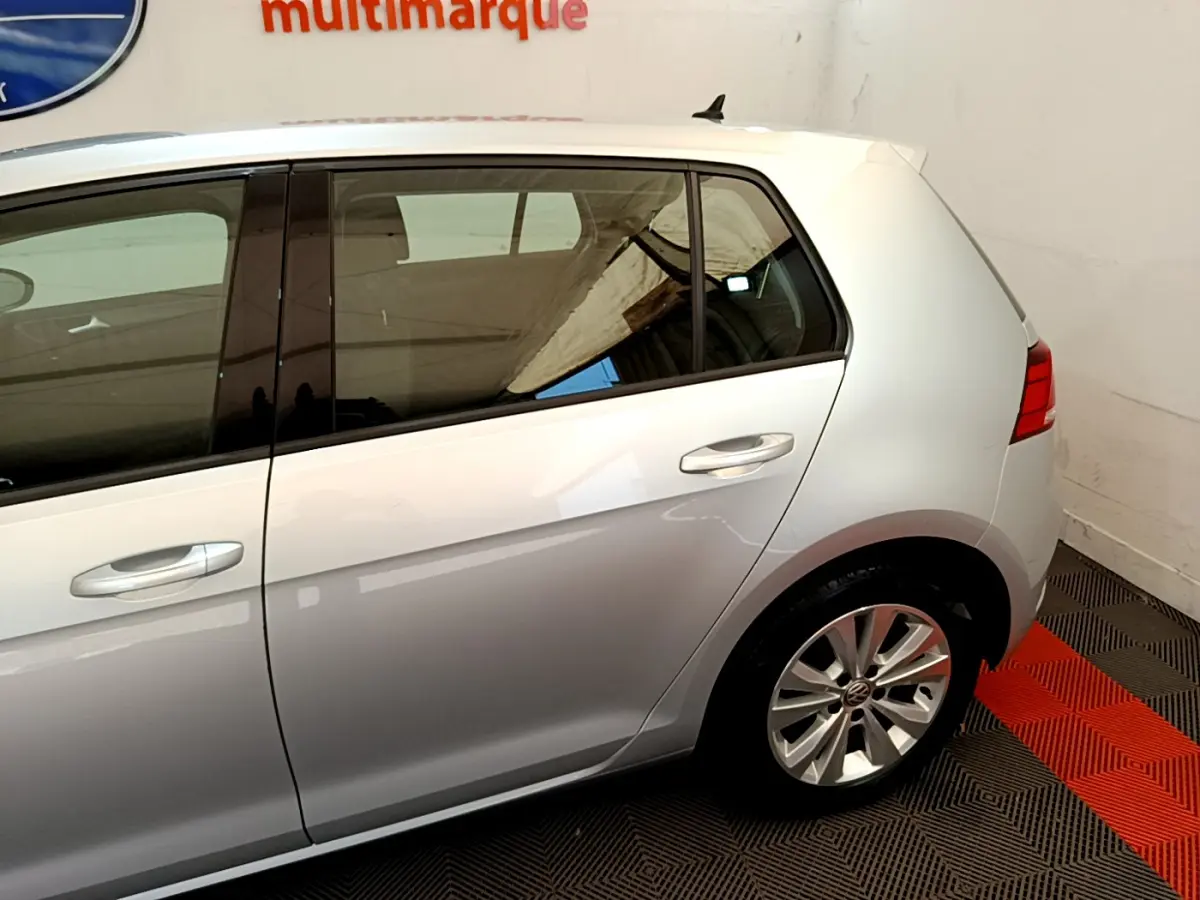 Vue côté droit arrière d'une Volkswagen Golf gris clair 2019 avec jante alliage et vitres teintées.