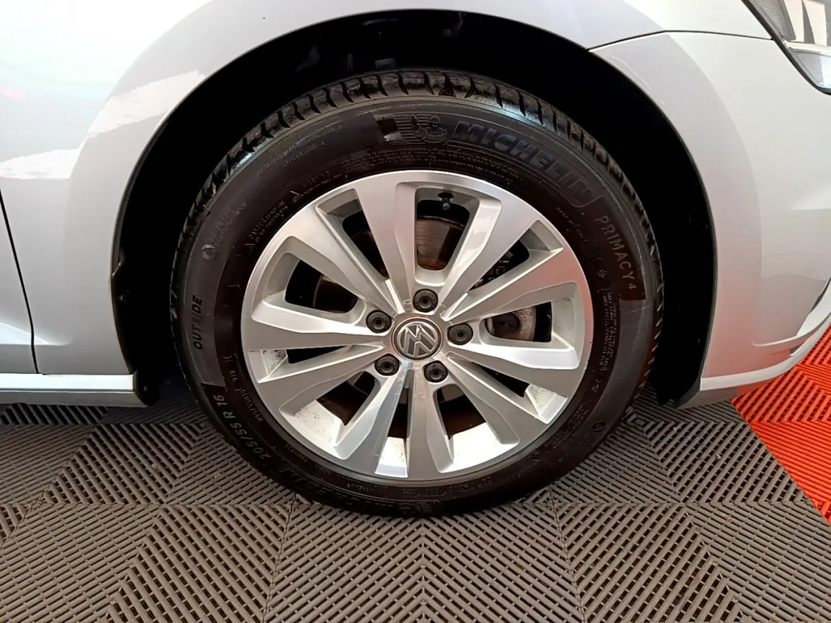 Gros plan sur la roue avant gauche gris clair d'une Volkswagen Golf 2019 avec jante alliage et logo VW central visible.