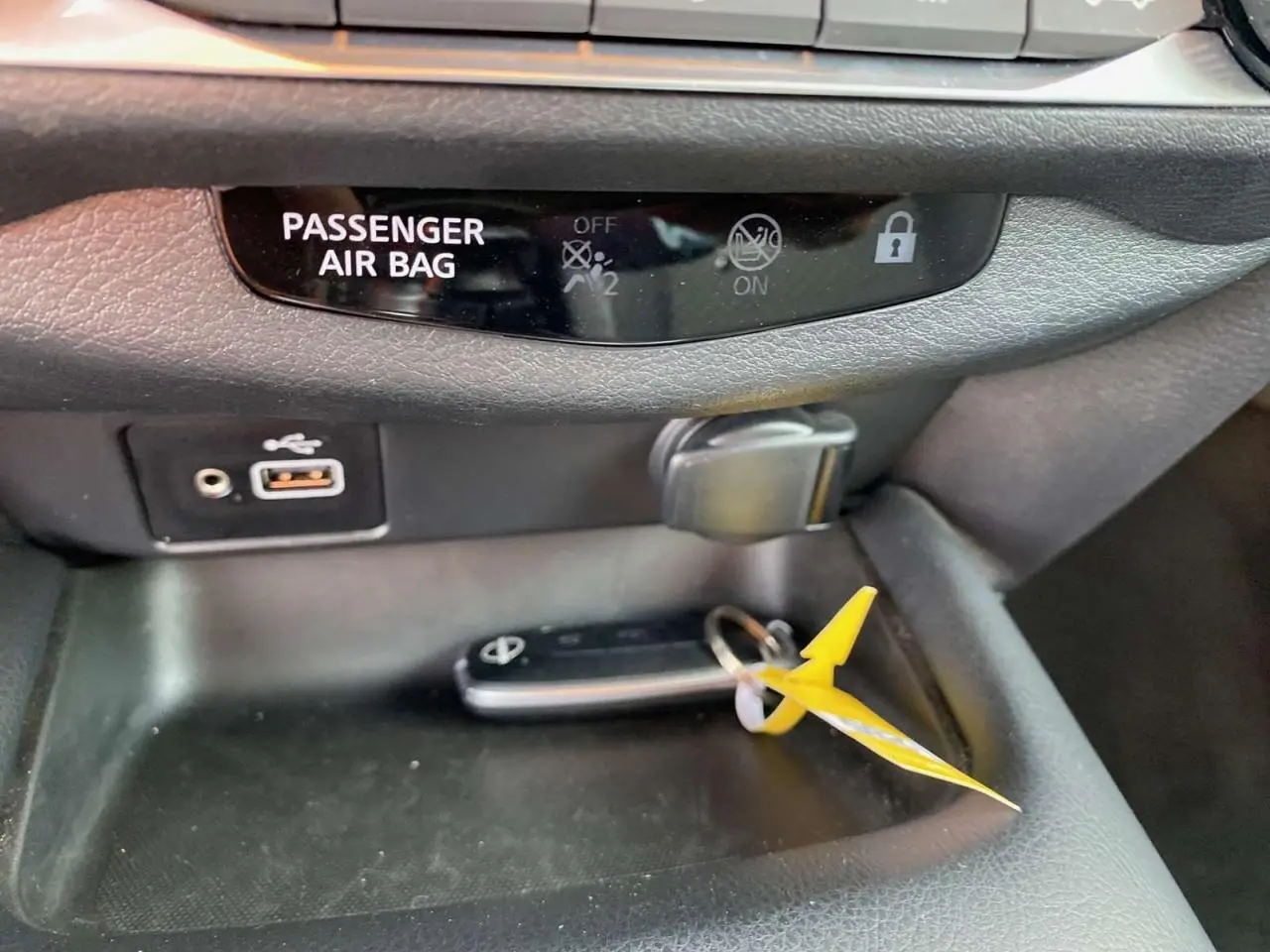 Gros plan sur la console centrale du Nissan Juke 2024 blanc perle, avec clé et ports USB visibles.