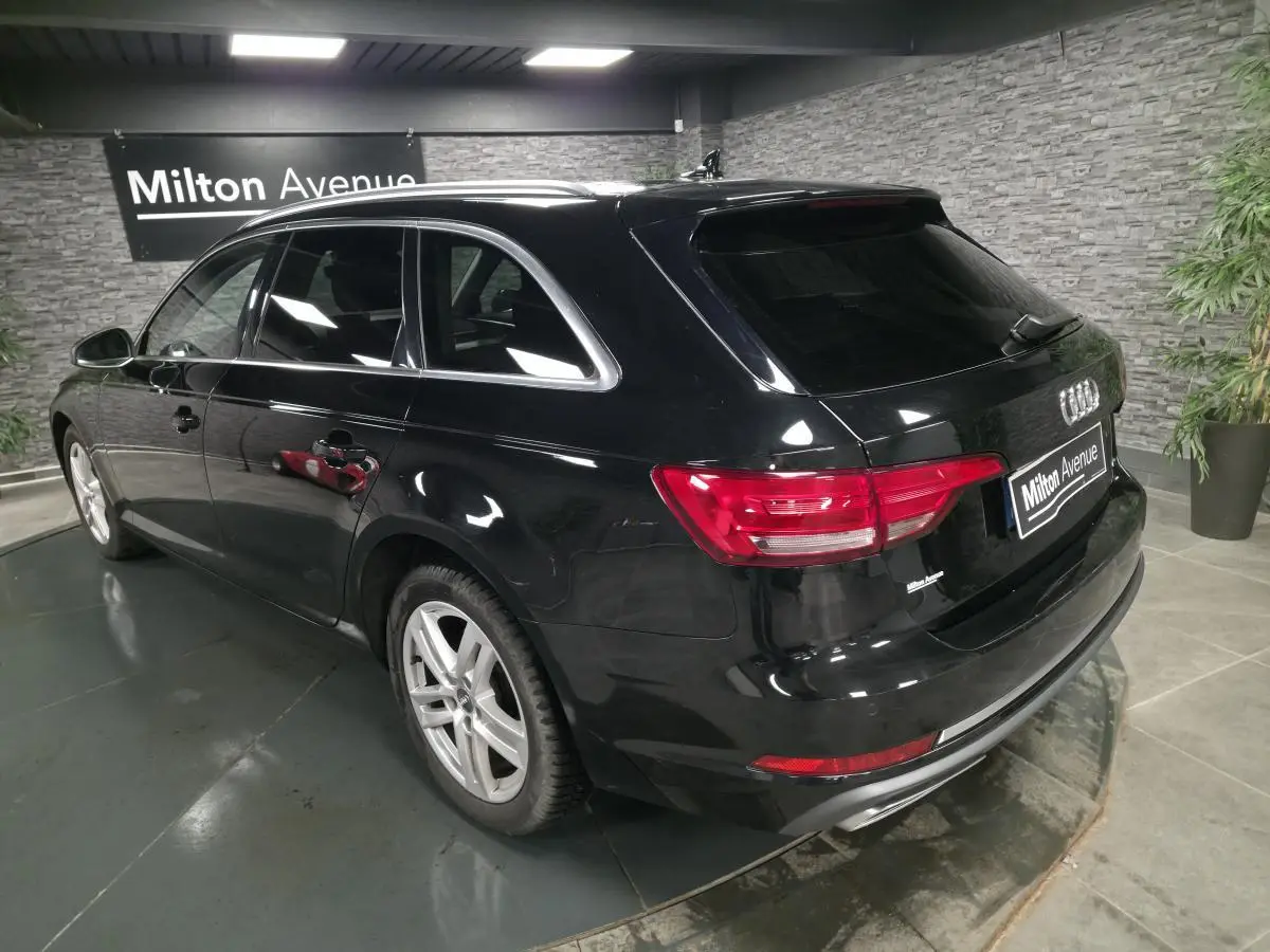 Audi A4 Avant noir vue 3/4 arrière droit en intérieur avec jantes aluminium 17 pouces et rétroviseurs noirs brillants