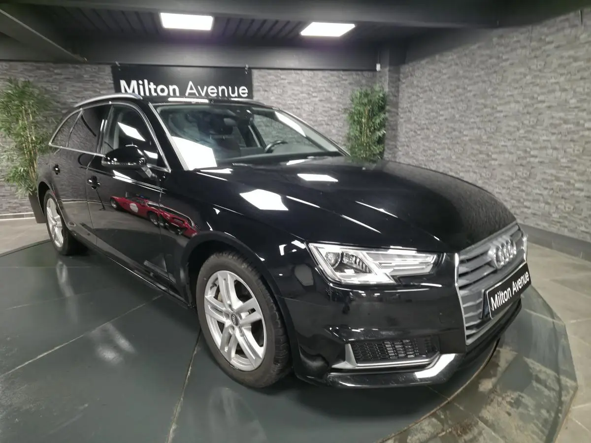 Audi A4 Avant noire vue en 3/4 avant droit dans un showroom avec jantes aluminium 17 pouces et rétroviseurs noirs brillants.