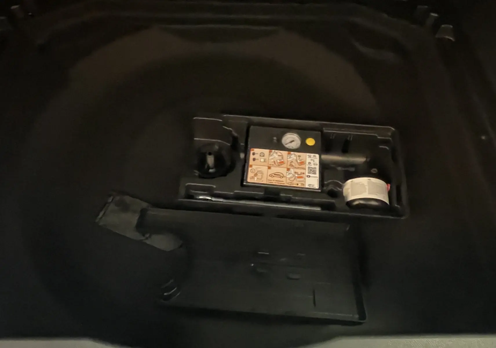 Détail du coffre d’un Citroën C5 Aircross hybride 2025 montrant le compresseur et kit de réparation pneus.