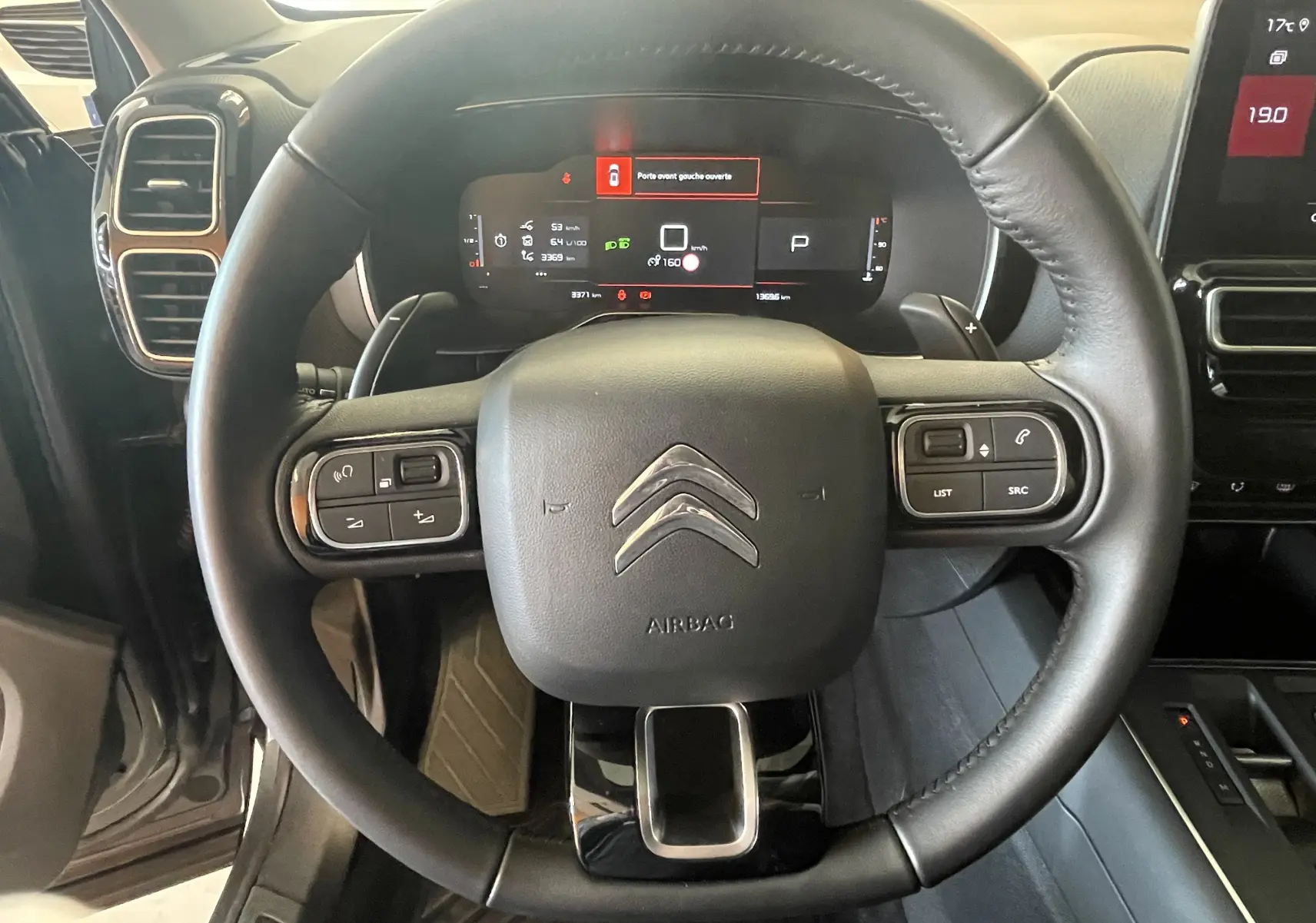 Vue rapprochée du volant cuir du Citroën C5 Aircross hybride 2025, avec commandes intégrées et tableau de bord numérique.