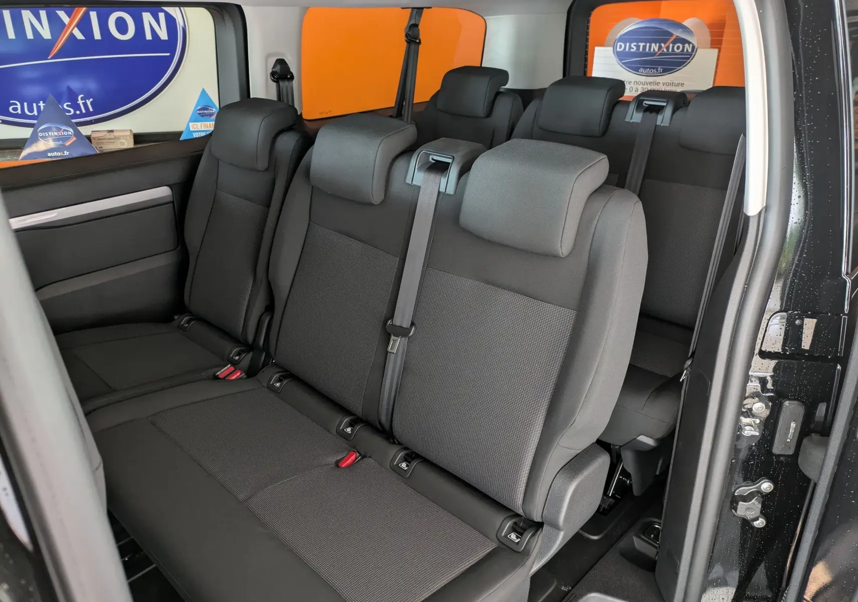 Vue intérieure côté droit du Peugeot Traveller noir 2026, montrant les sièges arrière en tissu noir sur trois rangées.