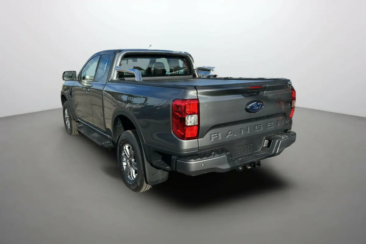 Ford Ranger gris carbone en 3/4 arrière droit avec rideau de benne et arceaux inox visibles.