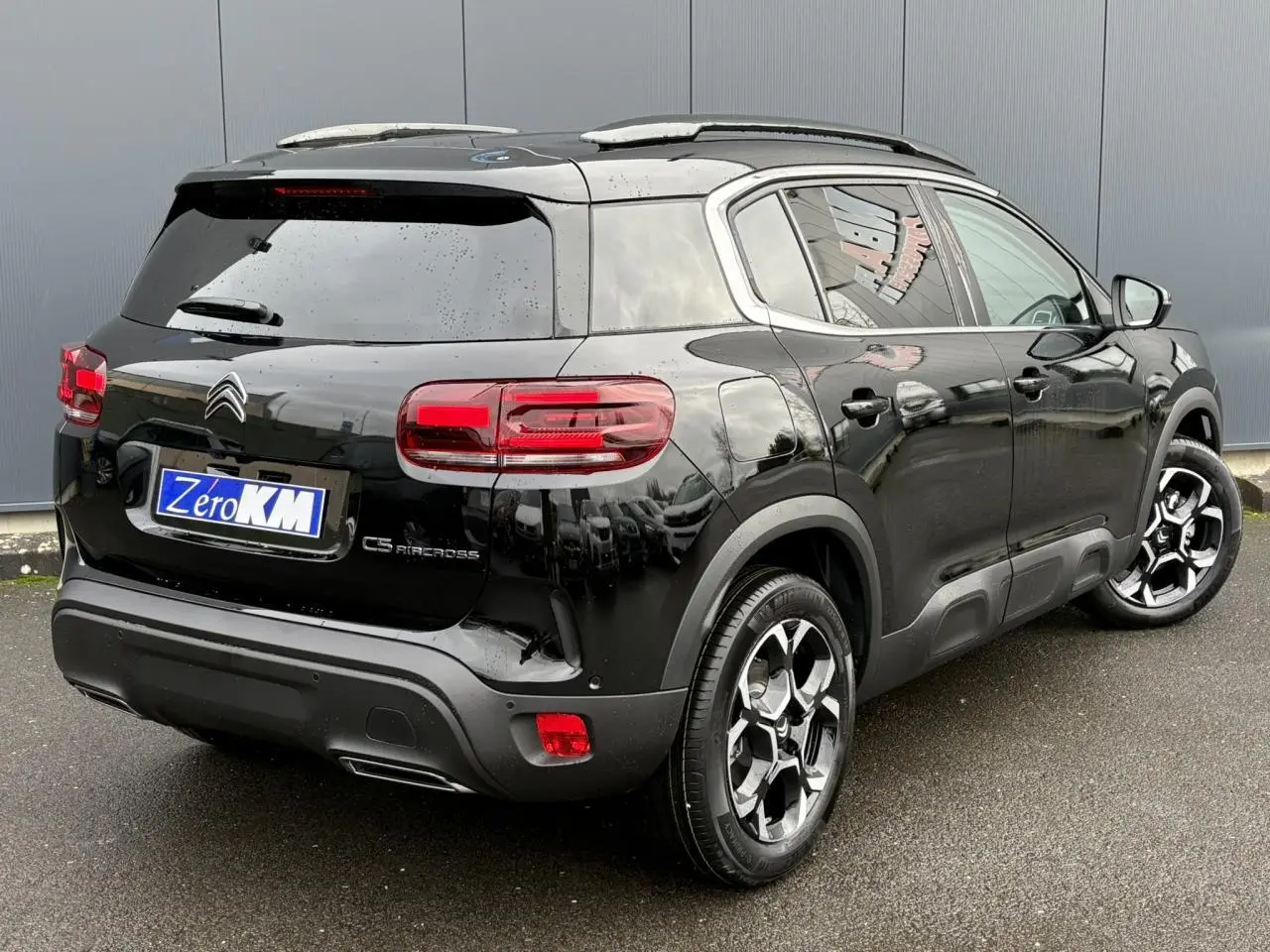 Vue 3/4 arrière droite du Citroën C5 Aircross noir Perla avec jantes alliage bi-ton et barres de toit noires.