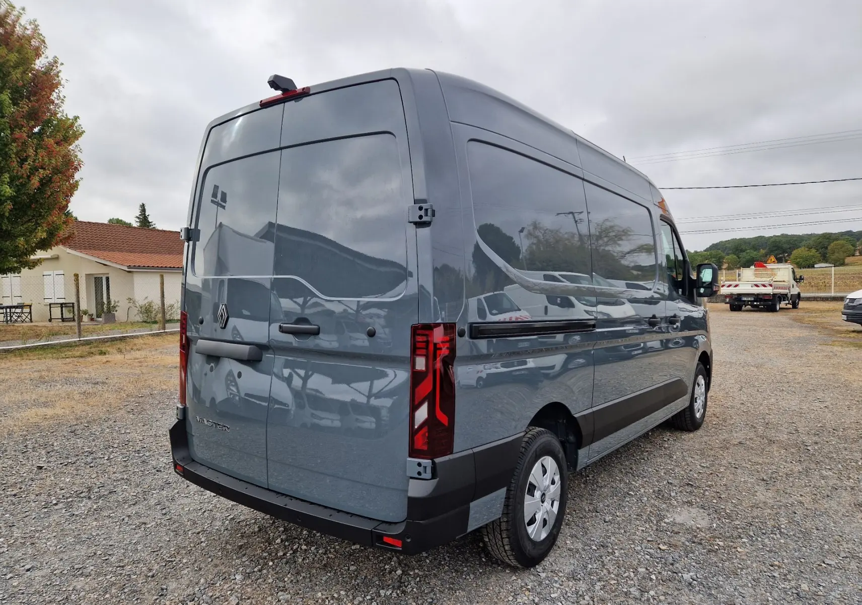 Vue 3/4 arrière droit d'un Renault Master L2H2 gris urbain, avec feux arrière verticaux et porte arrière pleine.