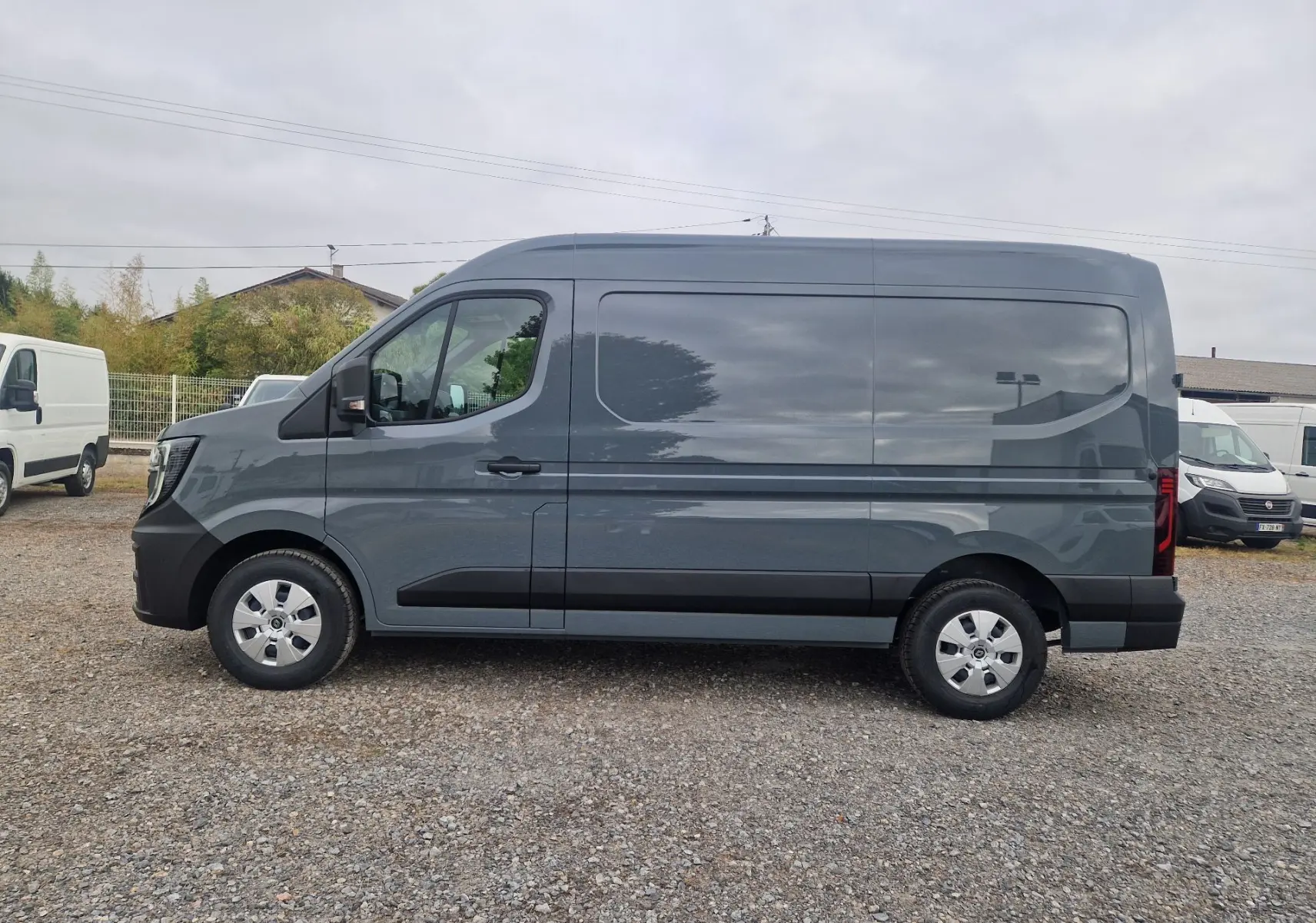 Renault Master gris urbain vu de profil côté gauche, fourgon utilitaire avec jantes acier et détails noirs sur les bas de caisse.
