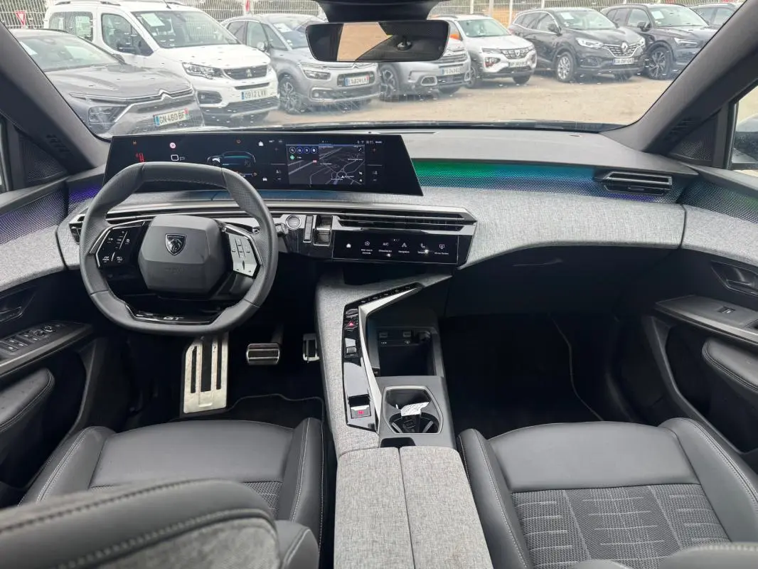 Intérieur moderne du Peugeot 5008 Hybrid noir, vue avant centrée sur le volant et le cockpit numérique large.