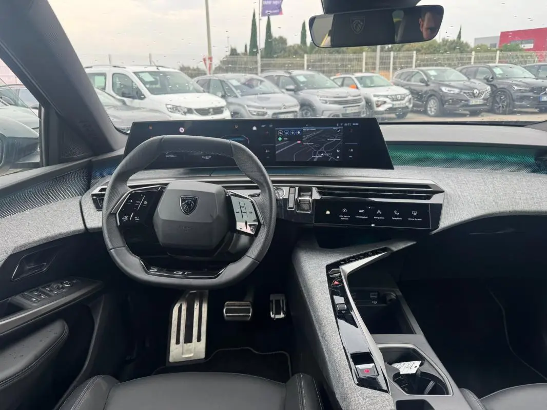 Vue intérieure avant du Peugeot 5008 Hybrid noir 2025, avec volant compact, écran numérique large et console centrale design.
