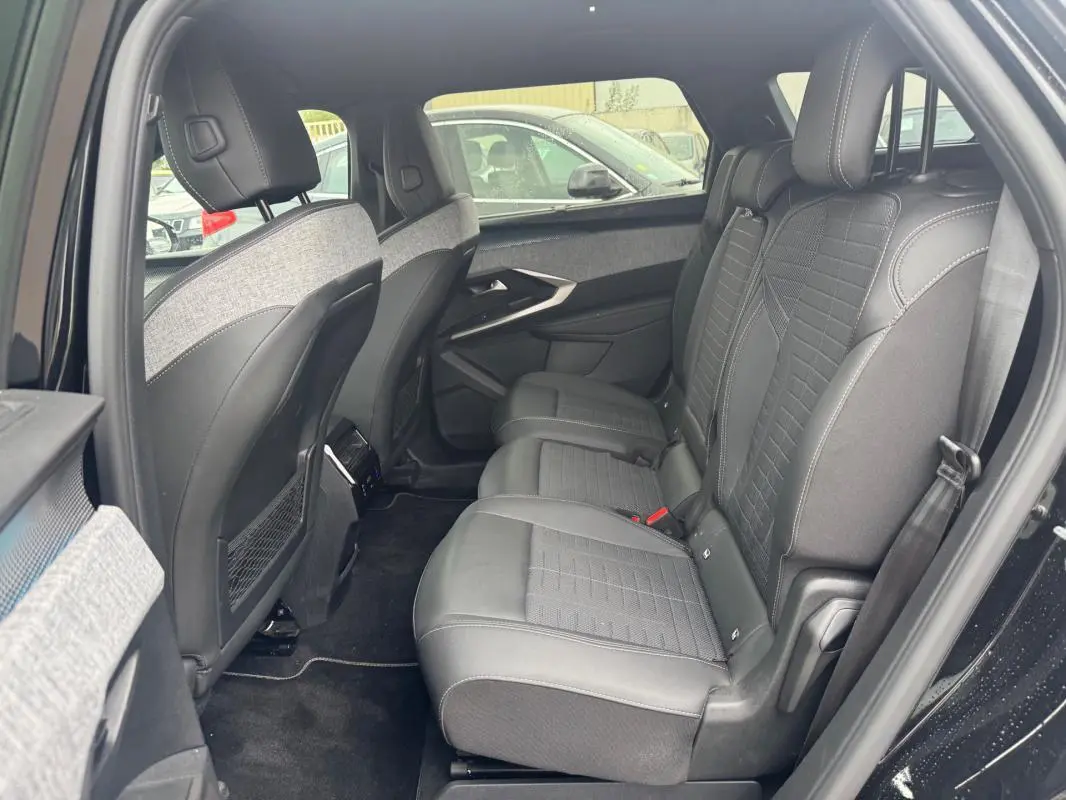 Vue intérieure côté droit des sièges arrière en cuir noir et tissu gris du Peugeot 5008 Hybrid 2025 avec appuie-têtes et ceintures visibles.