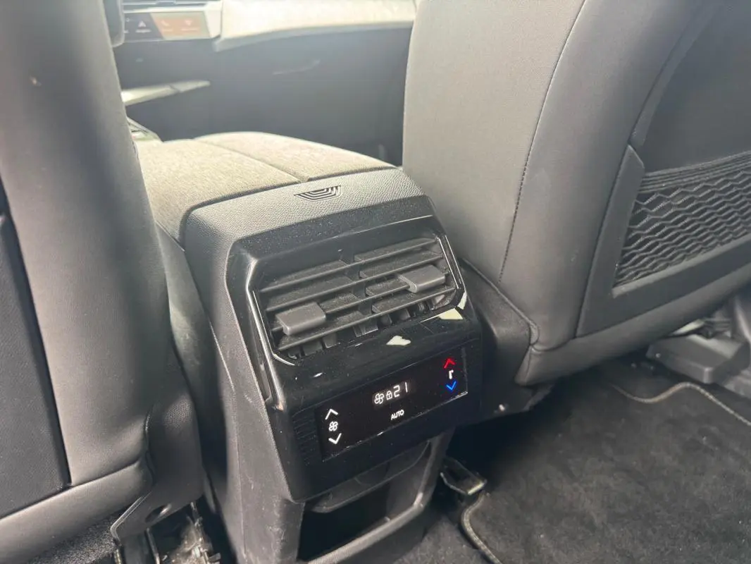 Vue rapprochée de la console arrière noire du Peugeot 5008 Hybrid 145 ch avec commandes de climatisation digitale.