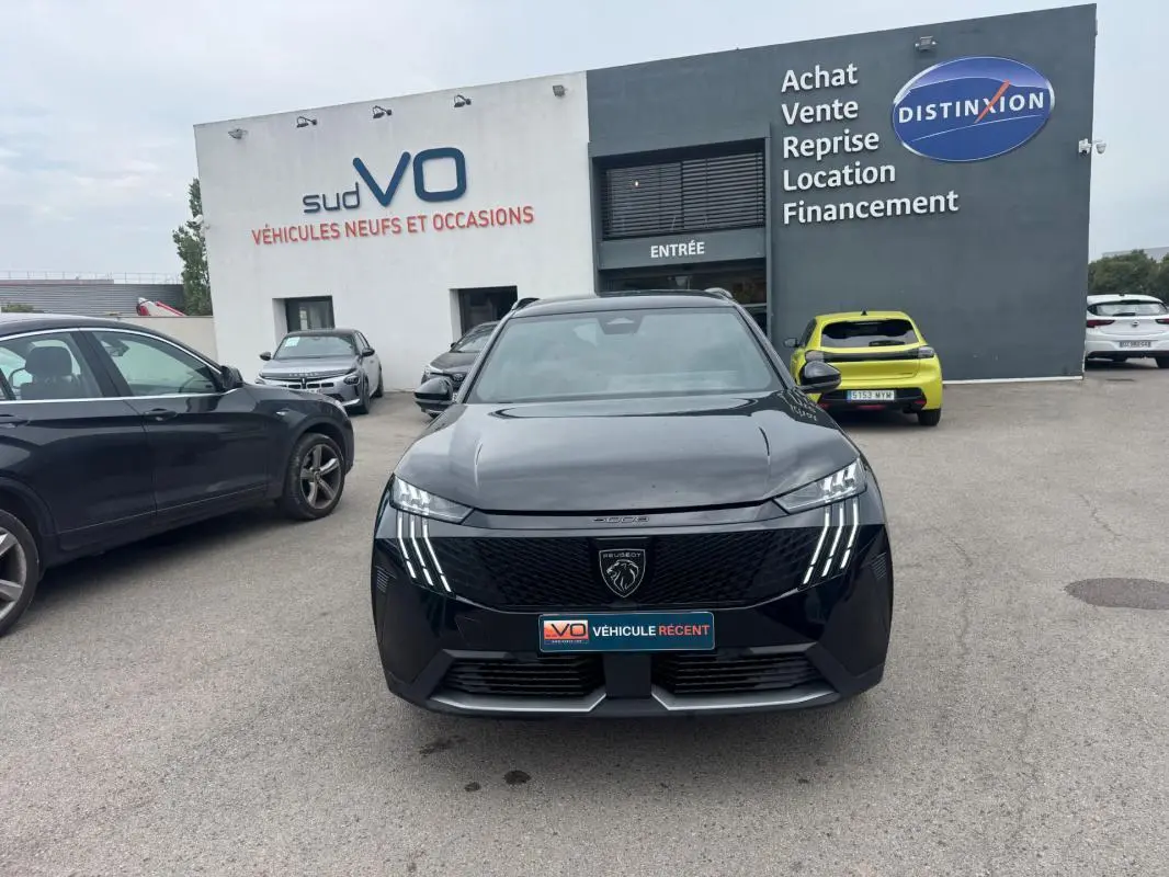 Vue de face d'un Peugeot 5008 Hybrid noir 2025 avec calandre distinctive et feux LED verticaux allumés.