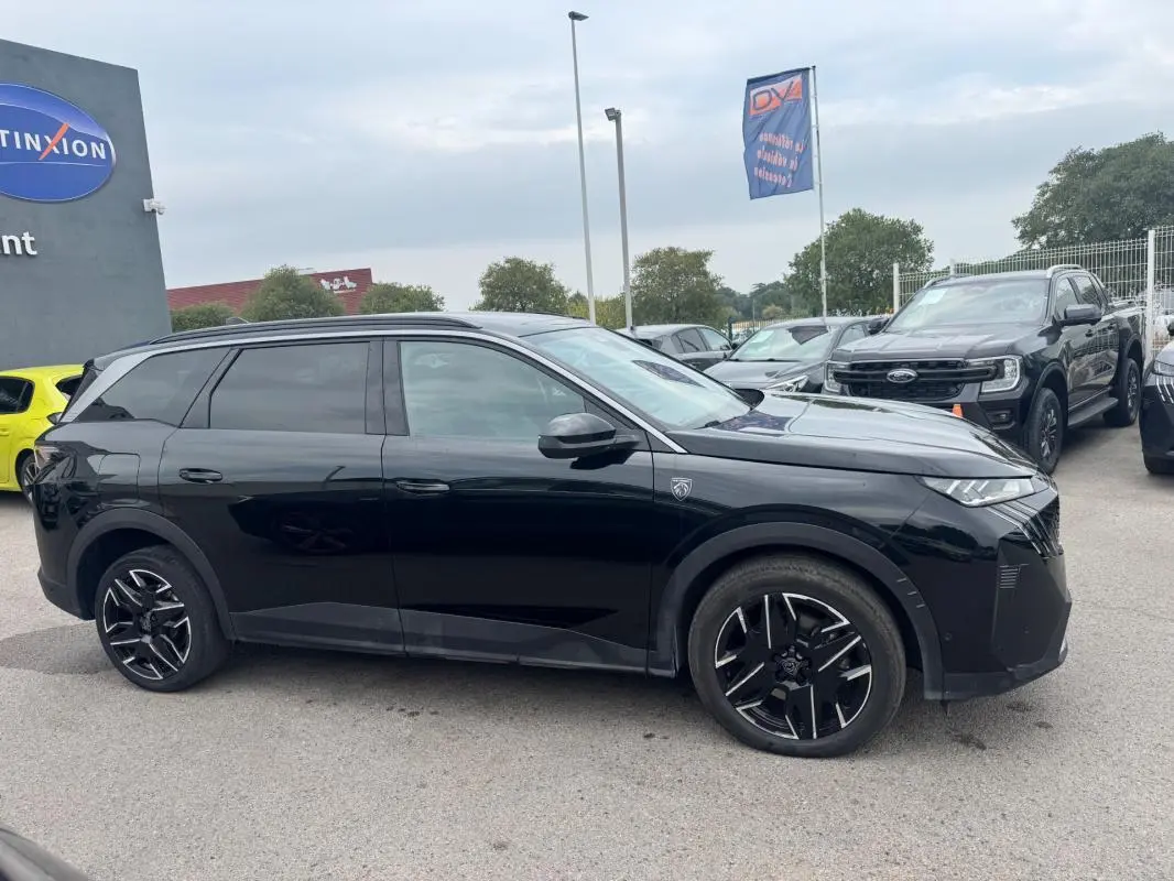 Peugeot 5008 Hybrid noir vue de profil côté gauche, avec jantes alliage noires et barres de toit visibles.
